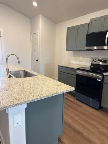 a kitchen with stainless steel appliances granite countertop a sink and a stove top oven with wooden floor