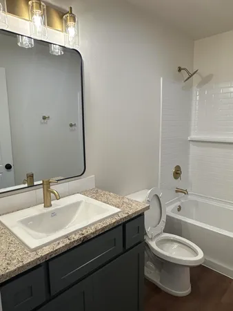 a bathroom with a granite countertop toilet sink and mirror