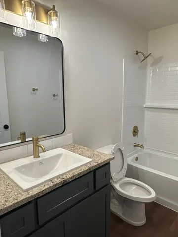 a bathroom with a granite countertop toilet sink and mirror
