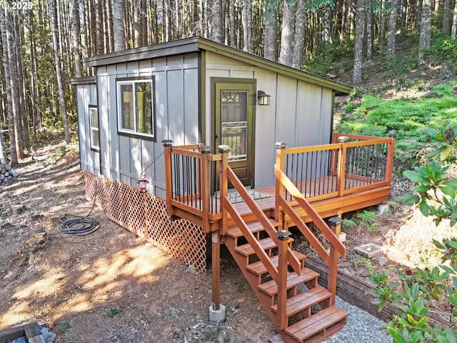 a view of a wooden house with a small yard and wooden fence