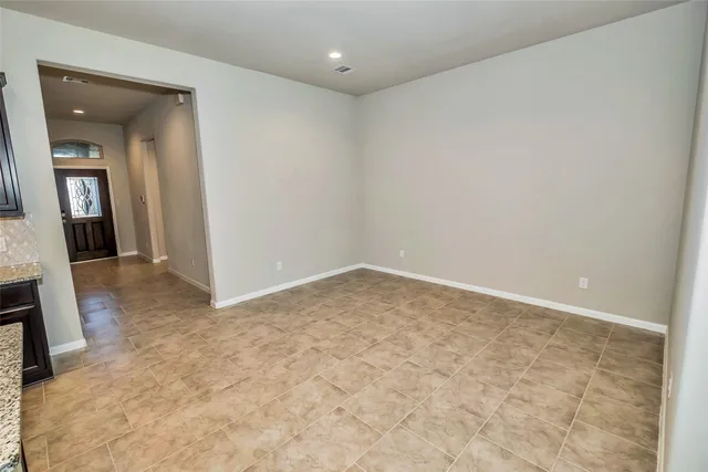 an empty room with a view of hallway with chandelier