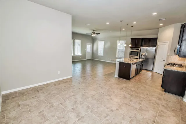 a kitchen with stainless steel appliances kitchen island granite countertop a refrigerator and a sink