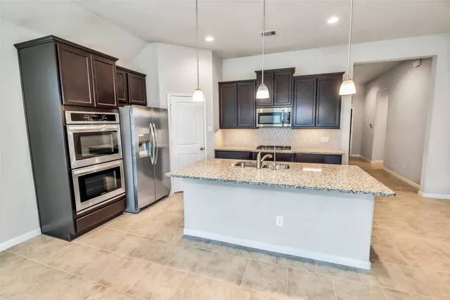 a kitchen with stainless steel appliances granite countertop a stove a refrigerator and a sink
