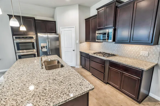 a kitchen with stainless steel appliances granite countertop a sink and a refrigerator
