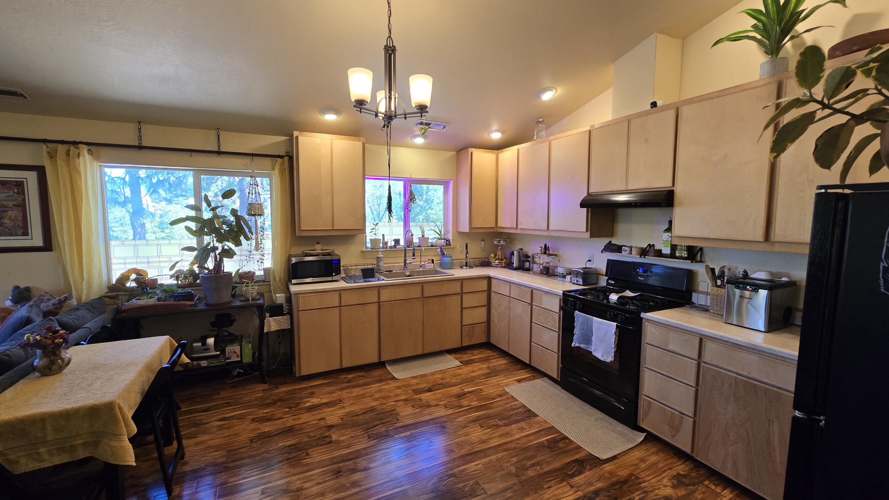 488 Crowson Road Ashland, OR 97520 - Photo 9 of 30 a kitchen with stainless steel appliances granite countertop wooden floors a stove and white cabinets