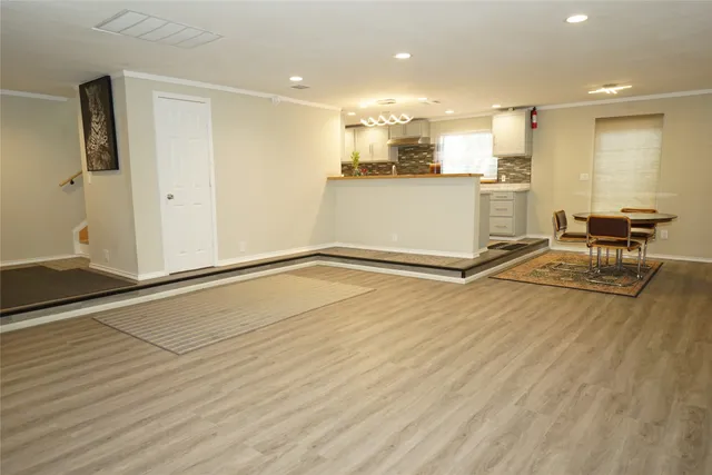 an empty room with wooden floor and kitchen view