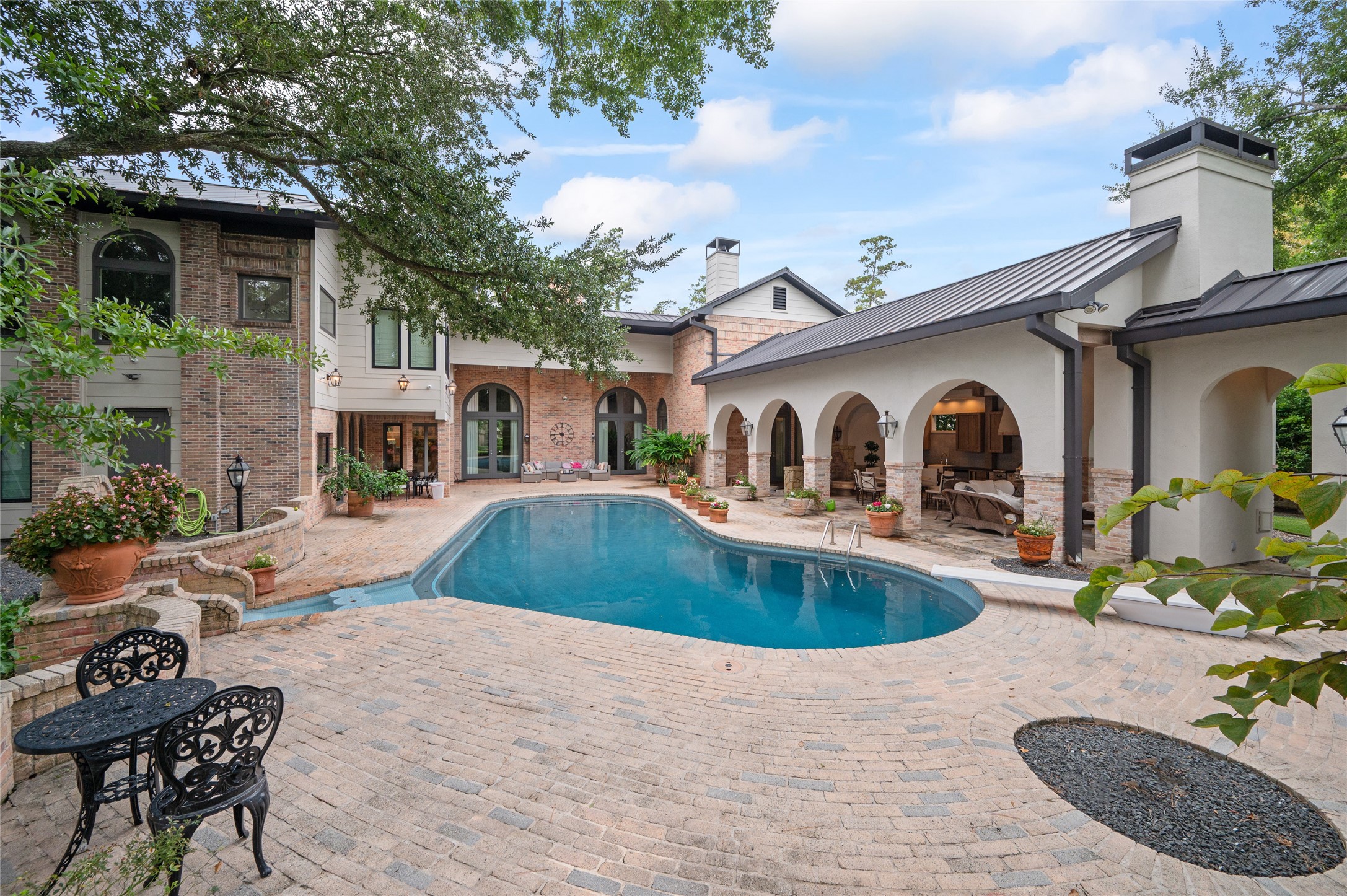 11518 Shadow Way Street Houston, TX 77024 - Photo 43 of 50 The backyard exudes a timeless resort-like ambiance with a glistening pool, outdoor pavilion, mature landscaping, and multiple seating areas perfect for gatherings or peaceful retreats.