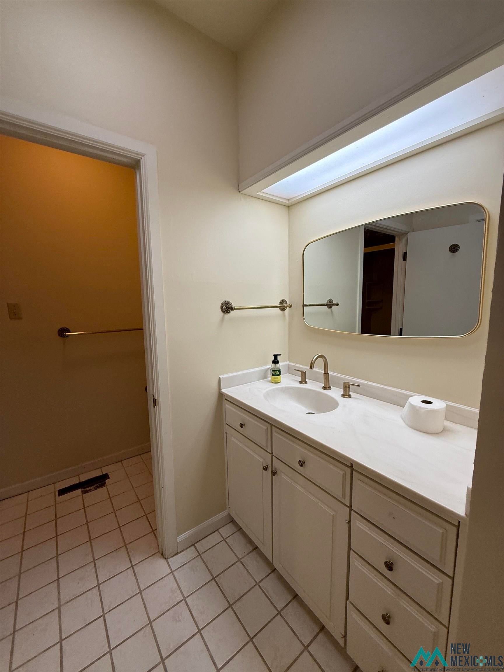 1111 West Country Road Roswell, NM 88201 - Photo 37 of 41 Bathroom vanity featuring a light-toned countertop with an integrated sink, brushed nickel faucet, and white cabinetry