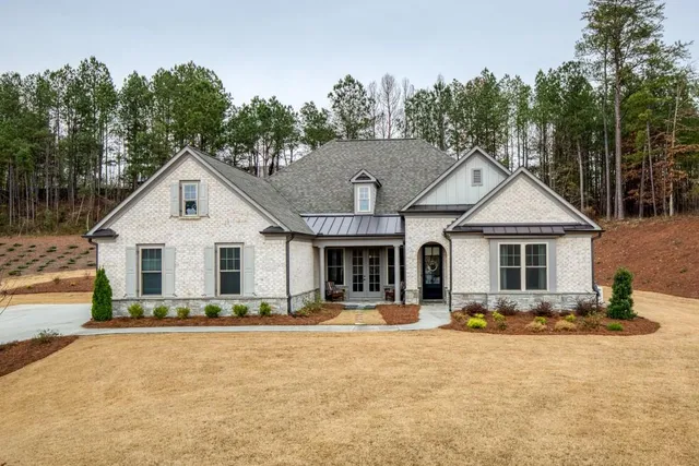 a front view of house with yard and trees in the background