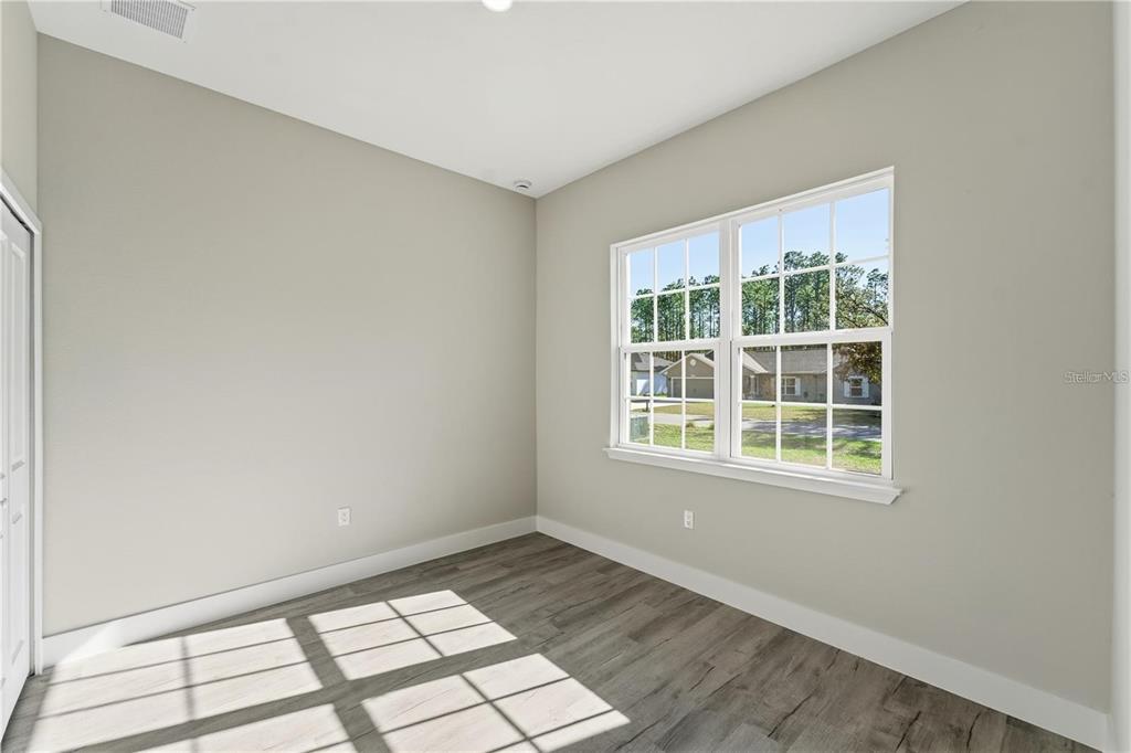 13205 Southwest 65th Circle Ocala, FL 34473 - Photo 18 of 32 an empty room with wooden floor and windows