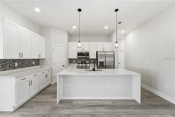 a view of a kitchen with kitchen island stainless steel appliances a large counter top and a fireplace