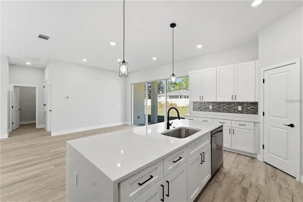 a kitchen with a sink chandelier and wooden floor