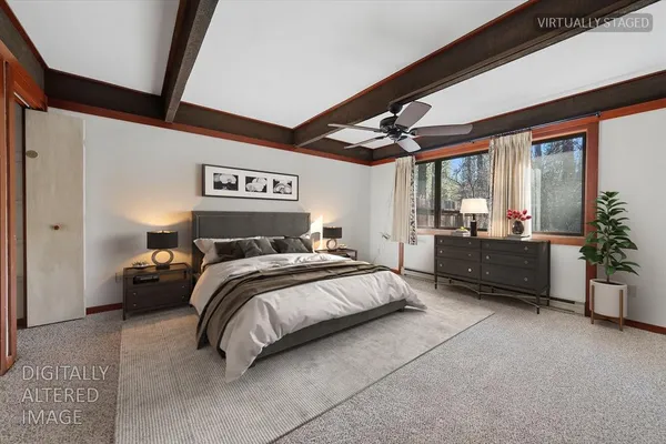 a spacious bedroom with a bed a dresser and paintings on the wall