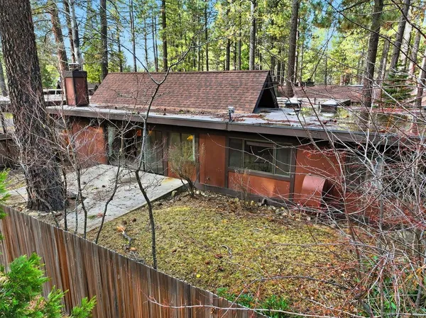 a view of a wooden house with large trees