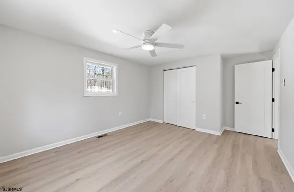 an empty room with wooden floor ceiling fan and windows