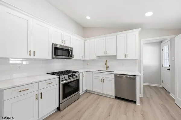 a kitchen with cabinets stainless steel appliances a sink and wooden floor