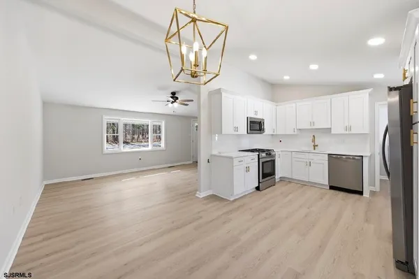 a kitchen with stainless steel appliances granite countertop a stove a sink dishwasher and a refrigerator with wooden floor