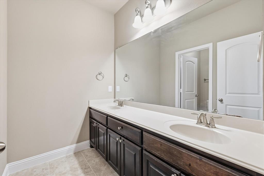 768 Huntingdon Street Coppell, TX 75019 - Photo 27 of 37 Secondary bath with long vanity, dual sinks, dark cabinetry, and a large mirror for easy shared use.