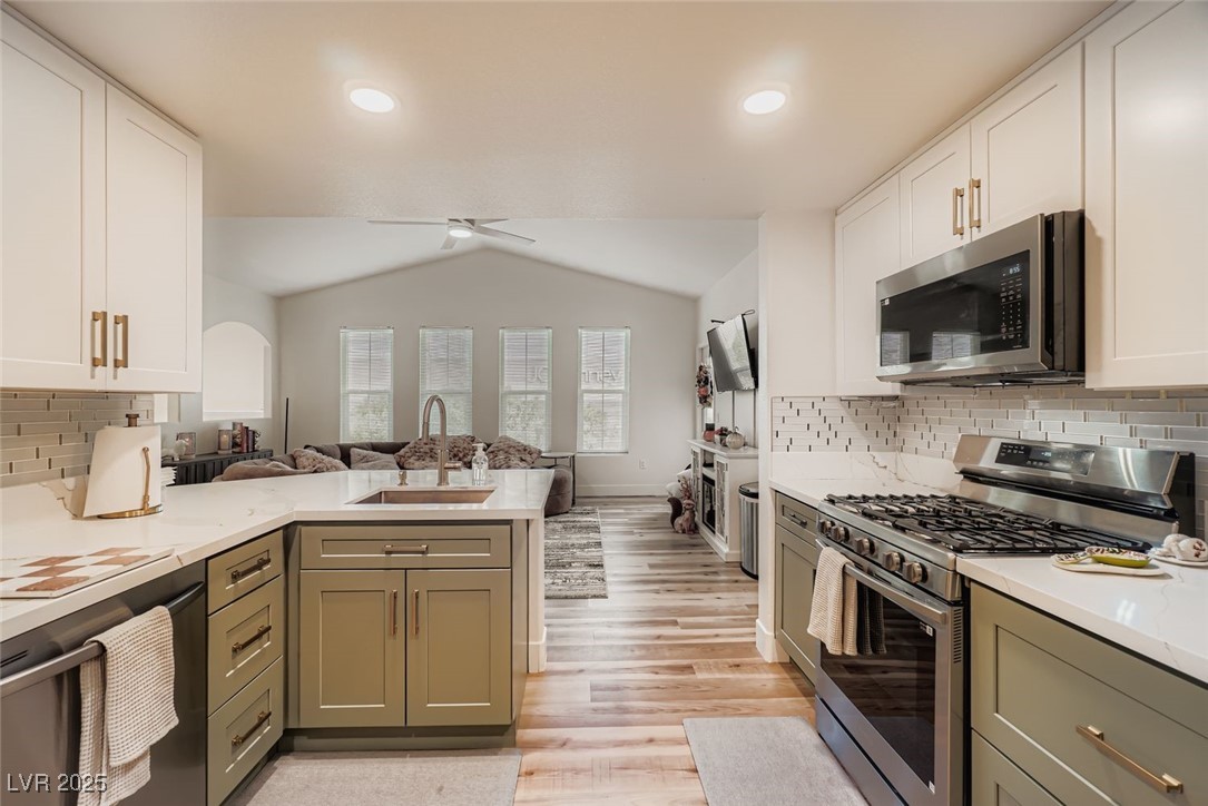 10001 Peace Way, Unit 2352 Las Vegas, NV 89147 - Photo 24 of 24 Kitchen featuring backsplash, stainless steel appliances, lofted ceiling, white cabinetry, and open floor plan