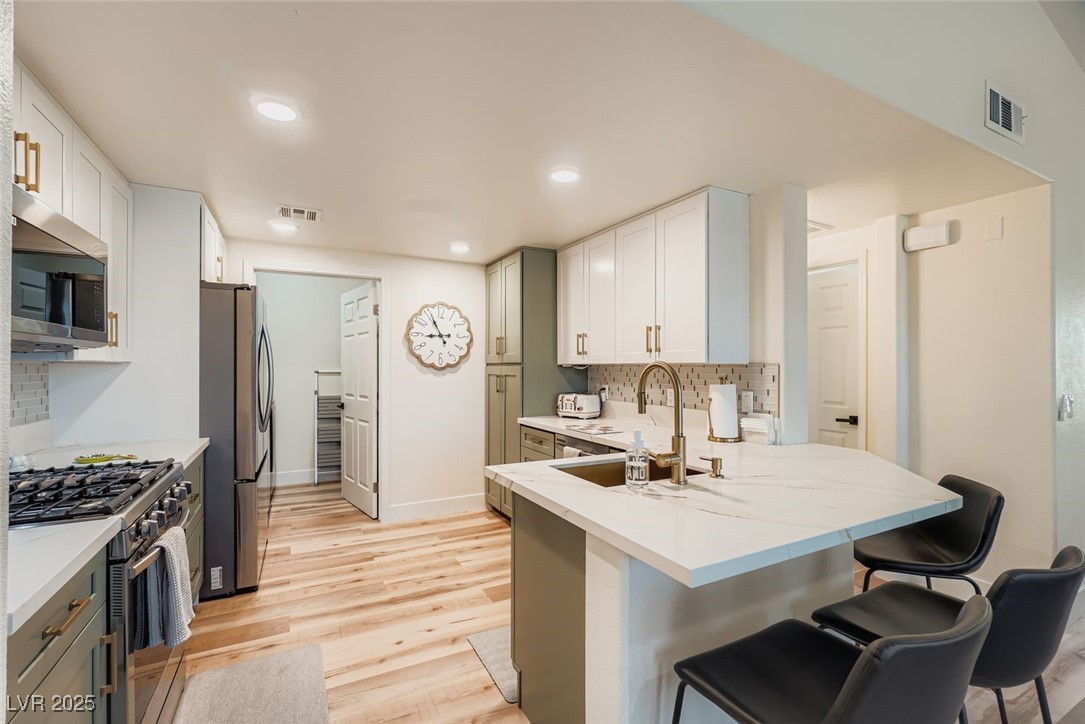 10001 Peace Way, Unit 2352 Las Vegas, NV 89147 - Photo 8 of 24 Kitchen featuring tasteful backsplash, appliances with stainless steel finishes, light wood finished floors, a kitchen breakfast bar, and recessed lighting