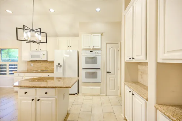 a kitchen with white cabinets and window