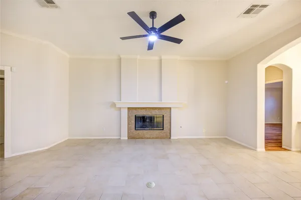 an empty room with chandelier fan and windows