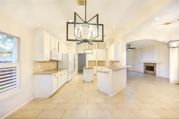 a large white kitchen with a stove a sink dishwasher and a fireplace