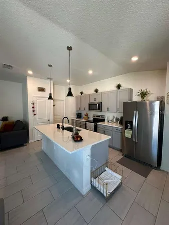 a large kitchen with a counter space a sink appliances and cabinets