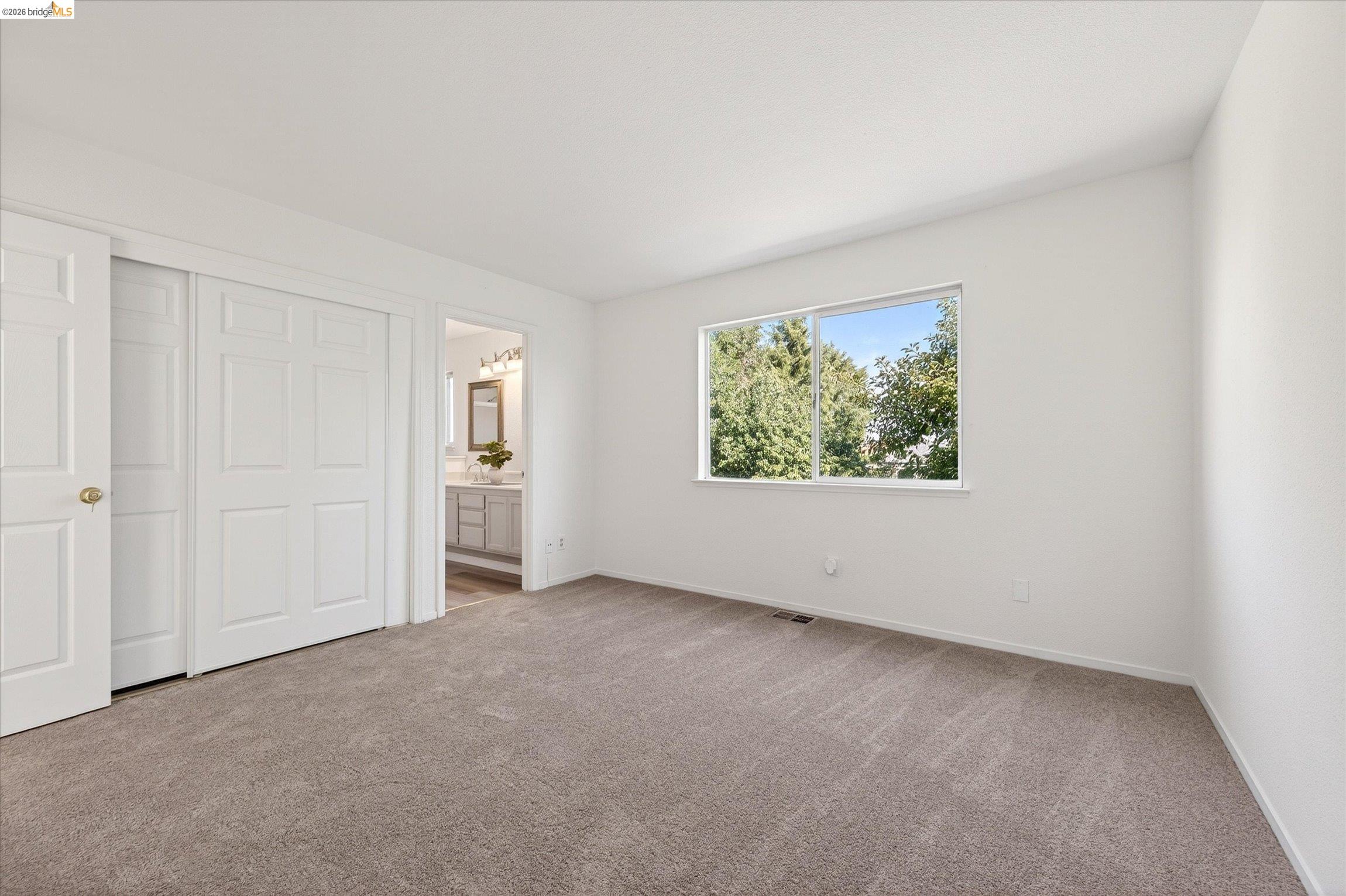 1120 Deerpark Road Oakley, CA 94561 - Photo 19 of 30 Carpeted room with white walls, a large window, a double bi-fold closet, and an en-suite bathroom featuring a vanity with a rectangular sink, wall-mounted mirror, and overhead lighting
