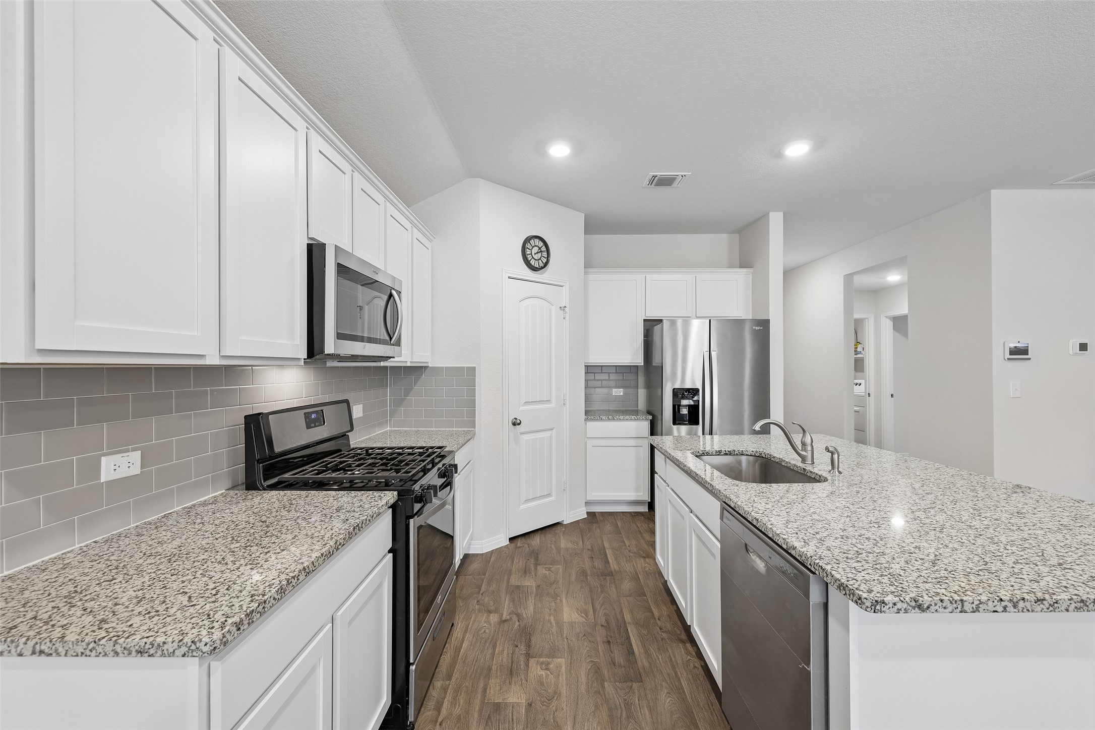 19805 Abigail Fillmore Road Manor, TX 78653 - Photo 13 of 40 A contemporary kitchen features bright white cabinetry and an inviting island with a deep sink.