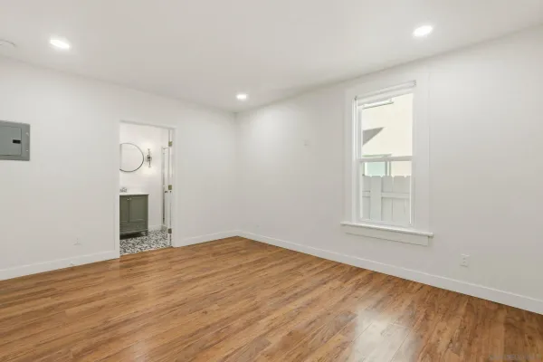 an empty room with wooden floor and windows