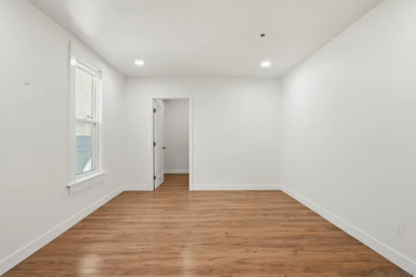 a view of an empty room with wooden floor and a window
