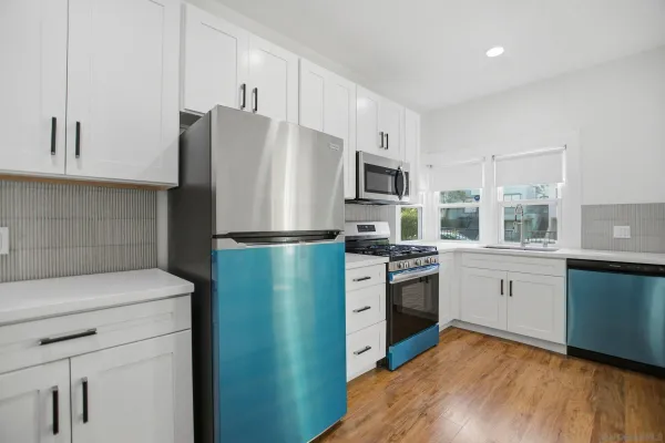 a kitchen with white cabinets and stainless steel appliances