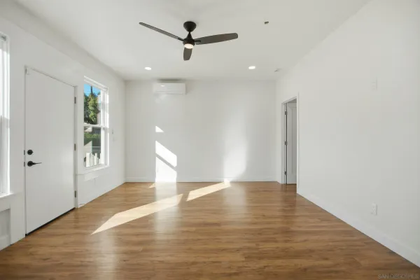a view of an empty room with window and wooden floor