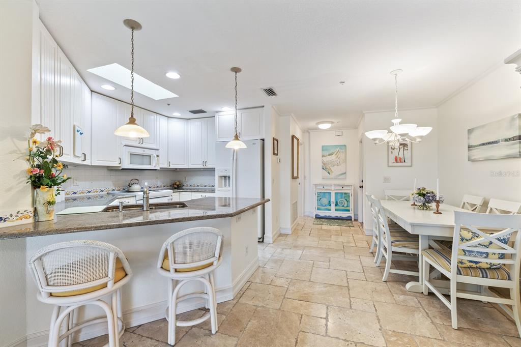 5856 Gasparilla Road, Unit MV28 Boca Grande, FL 33921 - Photo 5 of 21 a kitchen with stainless steel appliances kitchen island granite countertop a dining table chairs and white cabinets