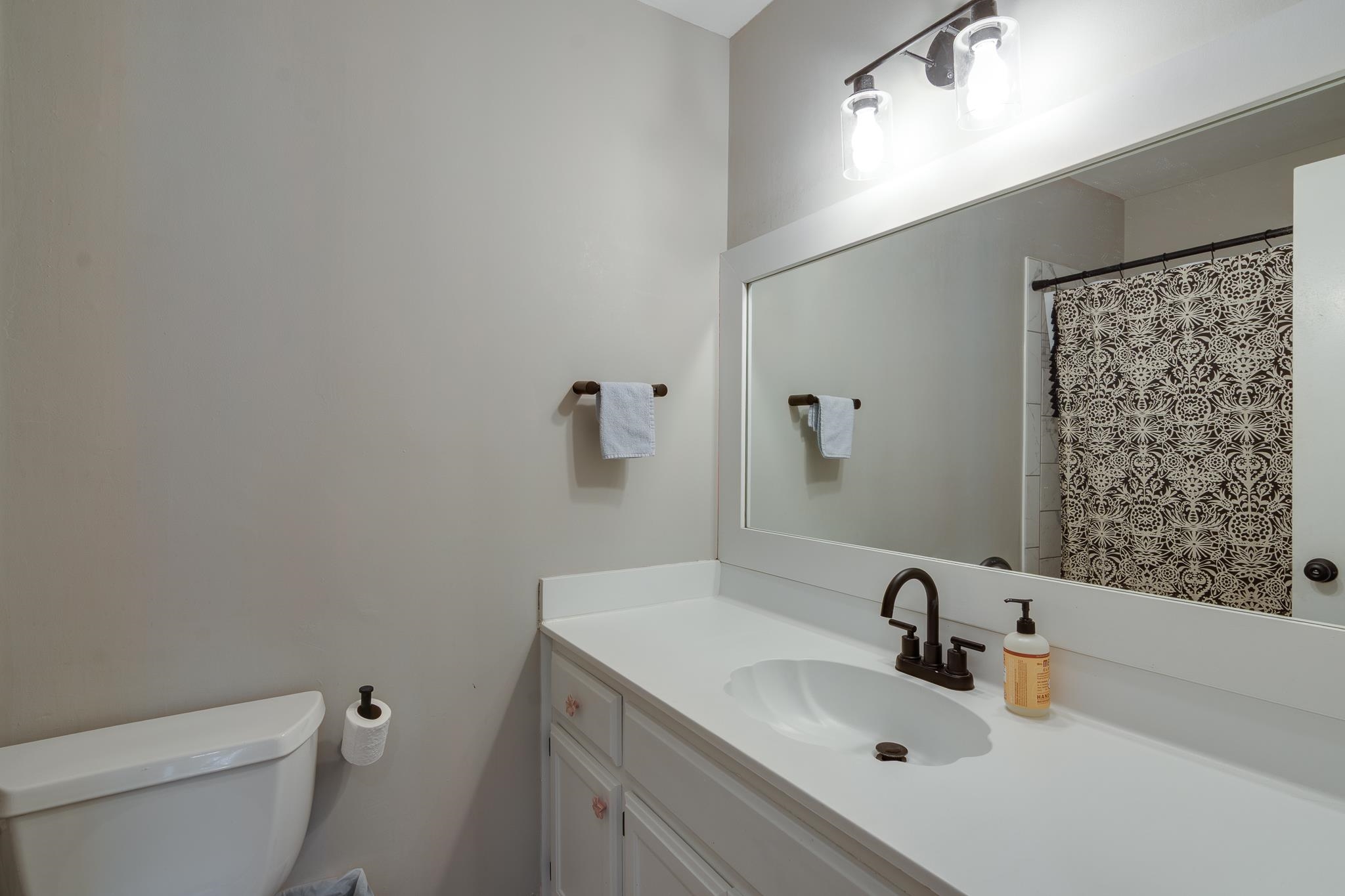 608 King Ridge Cove Collierville, TN 38017 - Photo 22 of 29 White vanity with a single basin sink, bronze-finish faucet, full-width mirror, and overhead light fixture