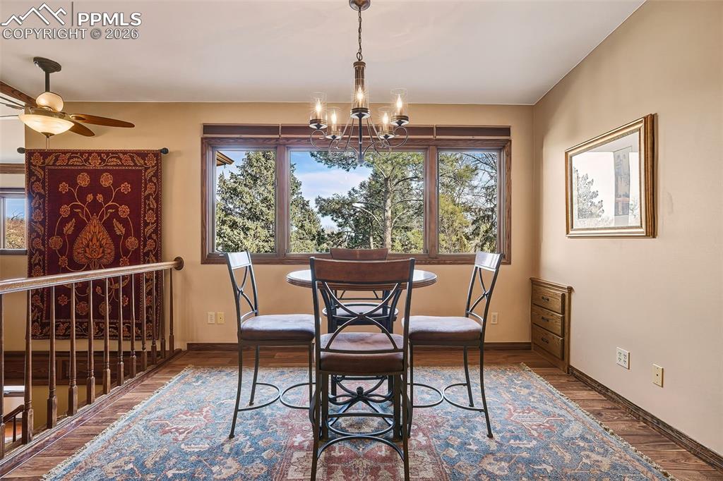 2771 Rigel Drive Colorado Springs, CO 80906 - Photo 17 of 50 Inviting dining space with wood flooring, statement chandelier, and expansive windows framing peaceful treetop views. Positioned perfectly for everyday meals or casual gatherings.