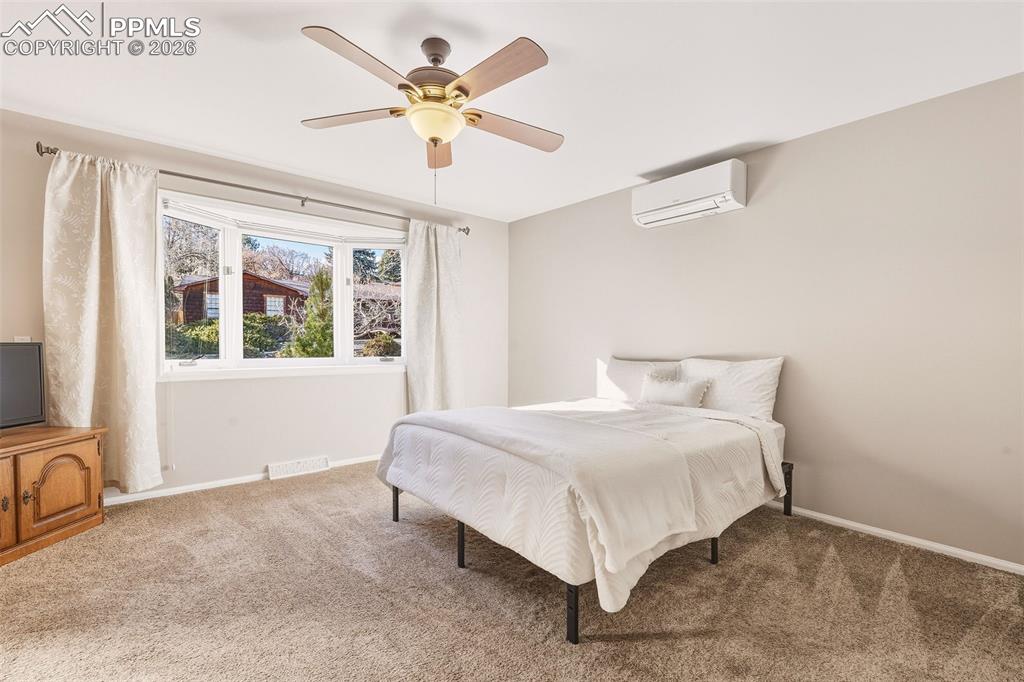 2771 Rigel Drive Colorado Springs, CO 80906 - Photo 18 of 50 Spacious main-level retreat with carpet, large picture window, ceiling fan, and wall-mounted mini split for individualized climate comfort.