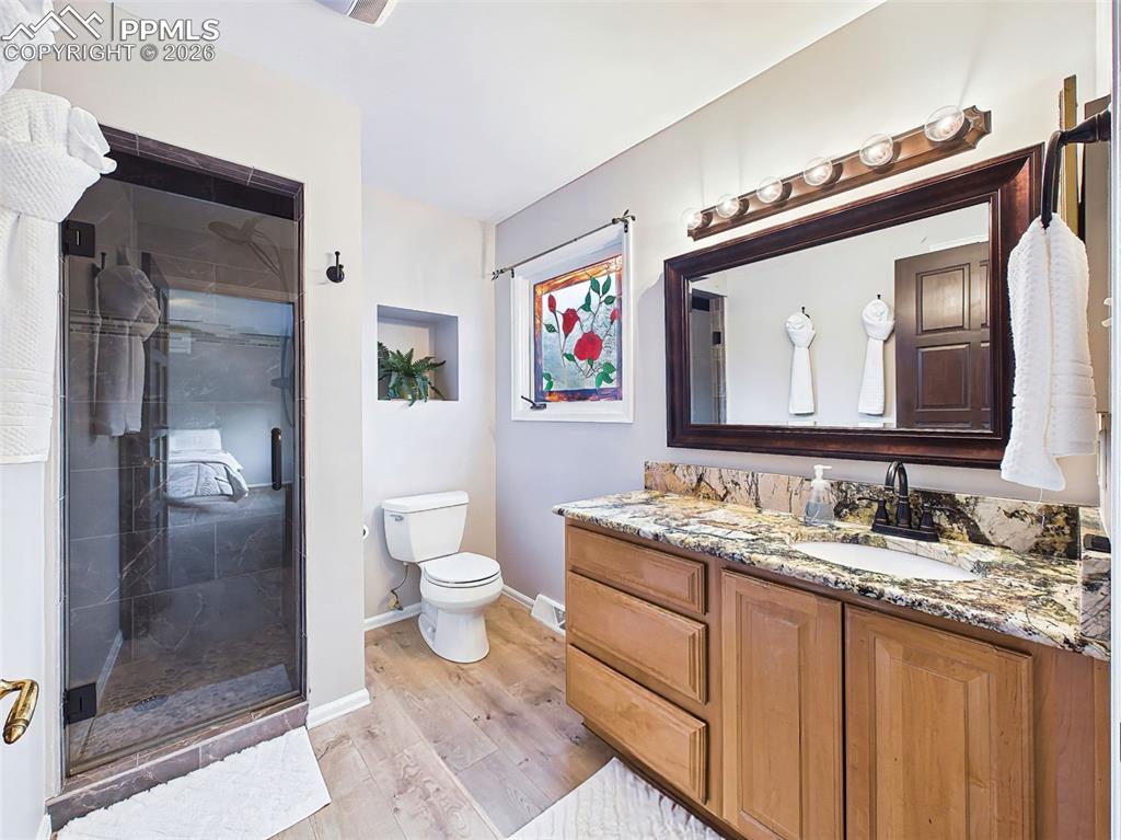2771 Rigel Drive Colorado Springs, CO 80906 - Photo 19 of 50 Updated three-quarter bath featuring a refinished walk-in shower, granite countertop, and warm wood cabinetry. Modern fixtures and upgraded flooring add both style and functionality.