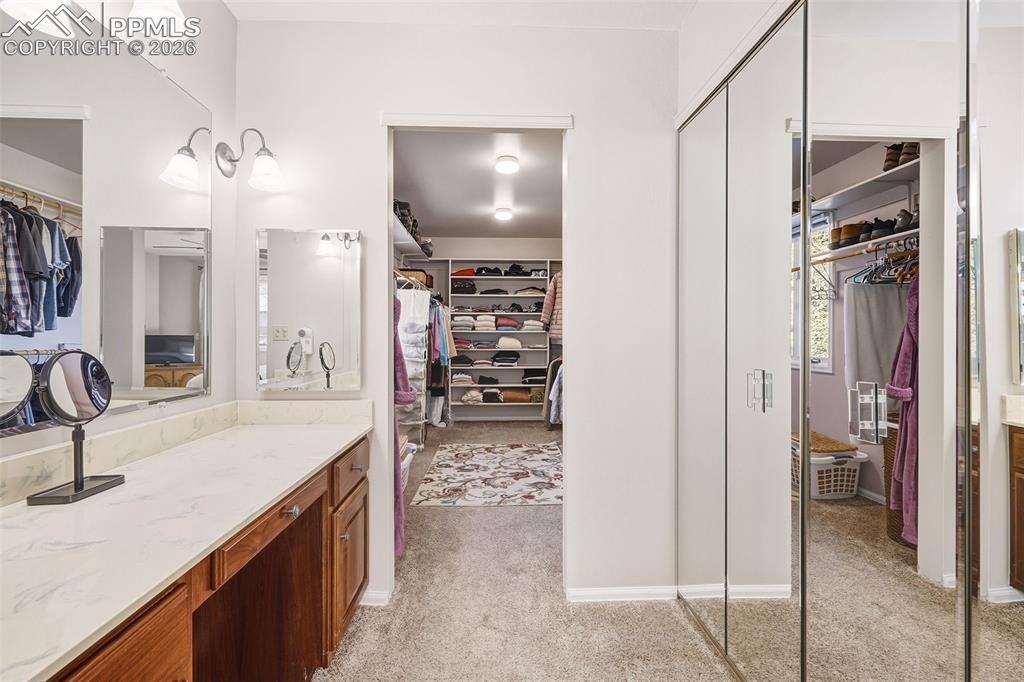 2771 Rigel Drive Colorado Springs, CO 80906 - Photo 20 of 50 Dedicated vanity space with countertop storage and dual mirrors, seamlessly connected to the expansive walk-in closet for added functionality.
