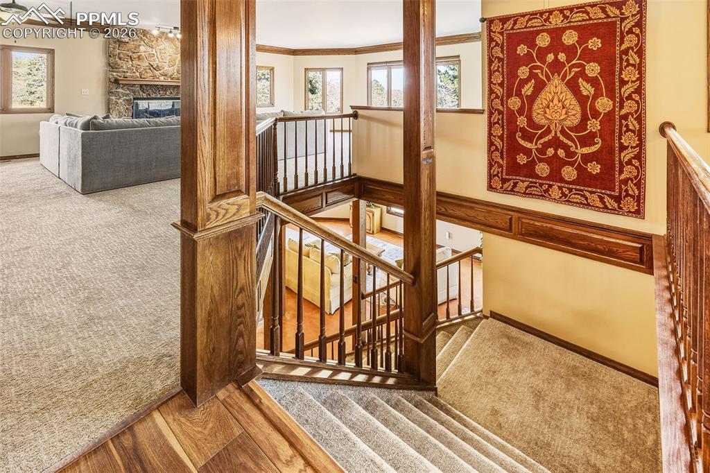 2771 Rigel Drive Colorado Springs, CO 80906 - Photo 28 of 50 Upper Landing & Staircase – Open stairwell with rich wood trim and railing detail overlooking both levels, creating architectural interest and visual connection throughout the home.