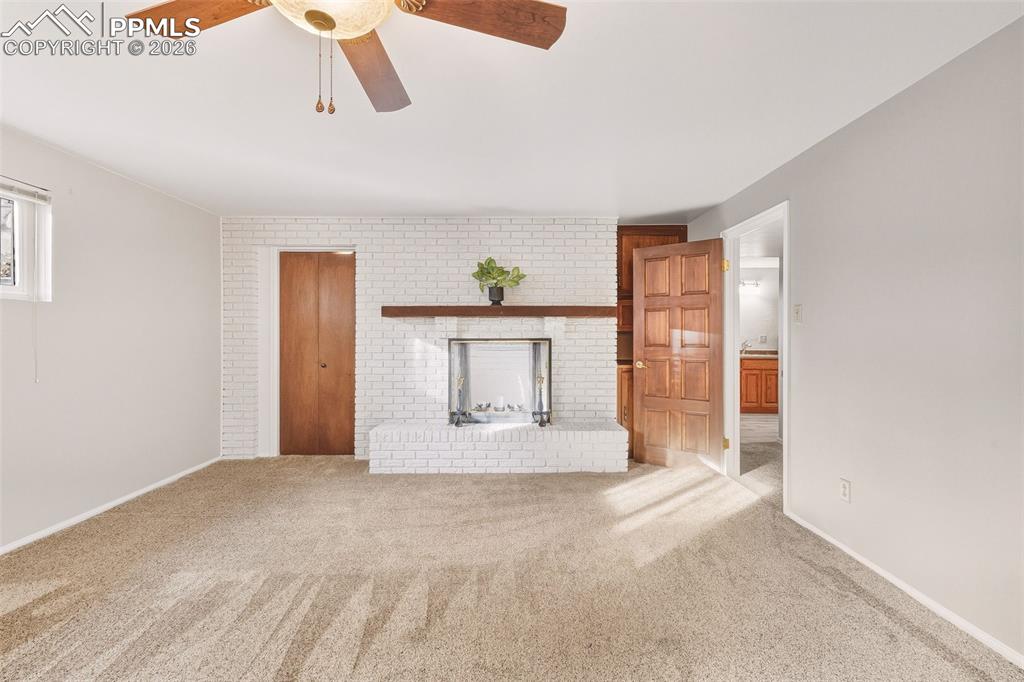 2771 Rigel Drive Colorado Springs, CO 80906 - Photo 32 of 50 Expansive bedroom #3 showcasing a white brick fireplace with wood mantel, generous floor space.