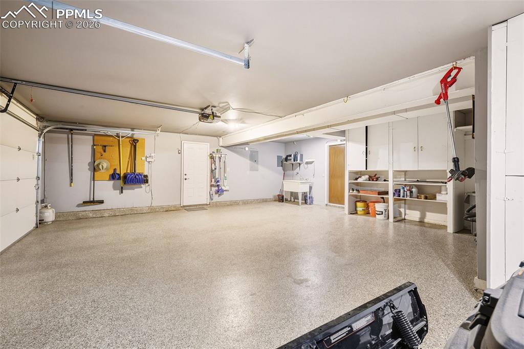 2771 Rigel Drive Colorado Springs, CO 80906 - Photo 37 of 50 Oversized garage with epoxy-coated flooring, built-in shelving, utility sink, and workshop space—designed for both storage and functionality.