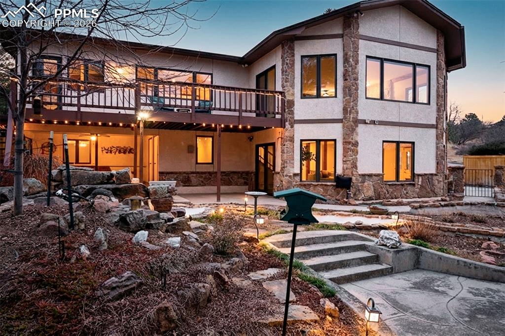2771 Rigel Drive Colorado Springs, CO 80906 - Photo 41 of 50 Stunning evening ambiance highlights the multi-level outdoor living spaces, upper deck, and covered patio below. Landscape lighting enhances both functionality and atmosphere.
