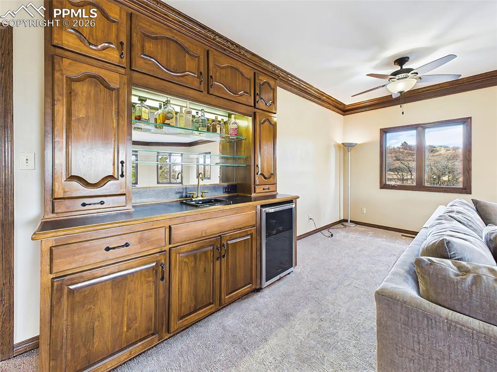 2771 Rigel Drive Colorado Springs, CO 80906 - Photo 7 of 50 Wet Bar – Custom built-in wet bar with glass shelving, accent lighting, sink, and beverage refrigerator—perfect for hosting guests or creating a cozy evening retreat.