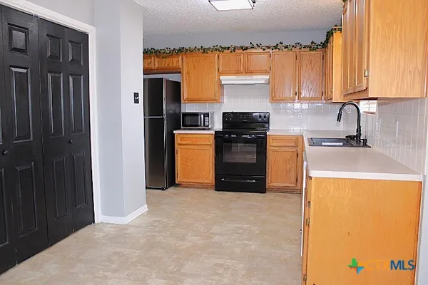 a kitchen with a refrigerator a stove a sink and a window
