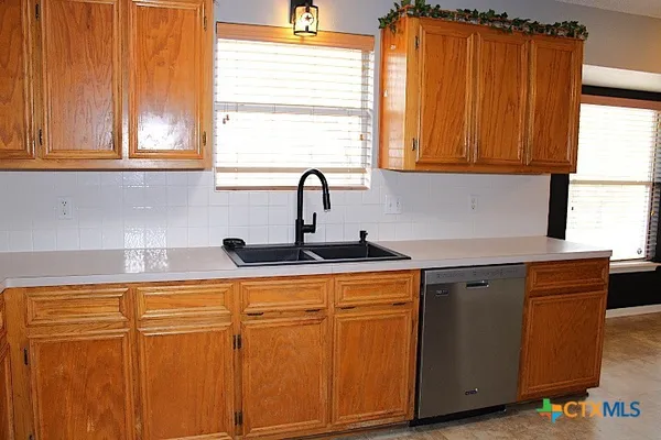 a kitchen with stainless steel appliances granite countertop wooden cabinets a sink and a window