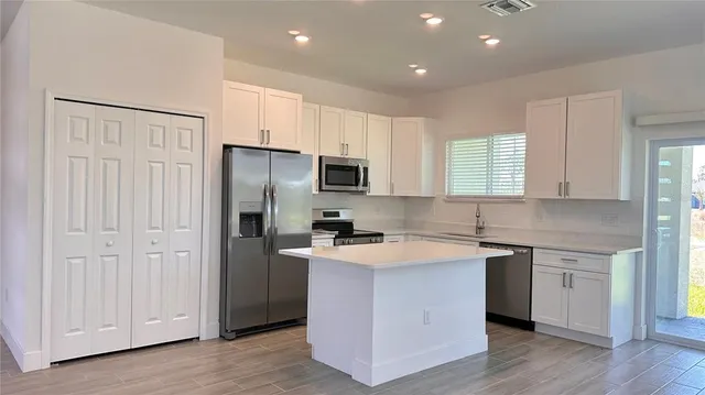 a kitchen with a sink a stove a refrigerator a center island and a window