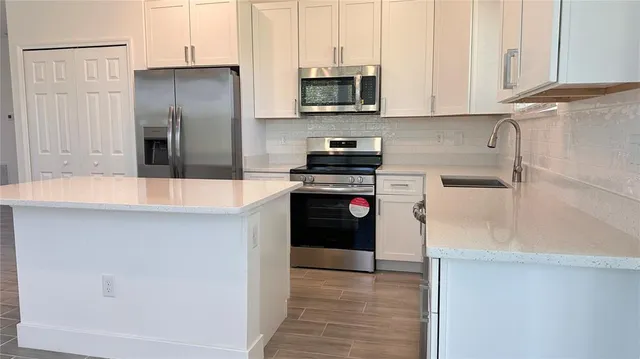 a kitchen with stainless steel appliances granite countertop a refrigerator a stove and a sink with wooden floor