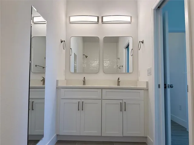 a bathroom with double vanity and a mirror